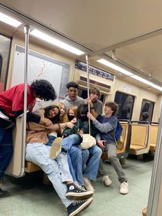 a group of people sitting on a subway car with their arms around each other,