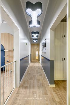 an empty hallway with wooden flooring and blue accents on the ceiling, along with white walls