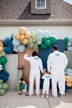 two adults and a child standing in front of balloons