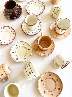 there are many cups and saucers on the table