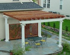 an outdoor patio with a table and chairs under a pergolated covered area next to a house