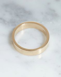 a gold wedding ring sitting on top of a white marble counter