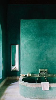 a bath tub sitting next to a window in a green room with white towels on it