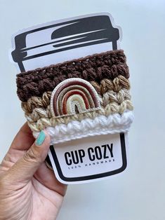 a hand holding up a cup cozy with crochet