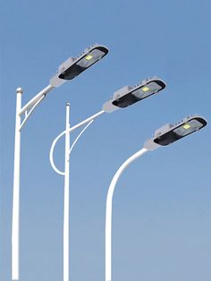 three street lights are shown against a blue sky with no one in the photo looking at them