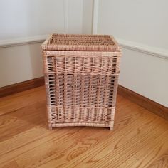 a wicker basket sitting on top of a hard wood floor next to a wall