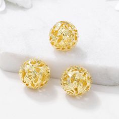 three pairs of gold earrings sitting on top of a white surface