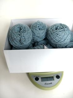 balls of yarn are in a box on a scale