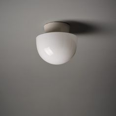 a white light hanging from the ceiling in a room with gray walls and flooring