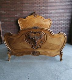 an antique bed with carved wood headboard and foot board in front of a brick wall