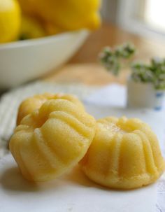 two yellow buns sitting on top of a table next to a bowl of lemons