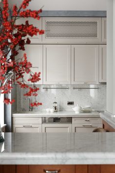 a vase filled with red flowers sitting on top of a kitchen counter