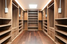 an empty walk - in closet with wooden shelves and shelving units on each side