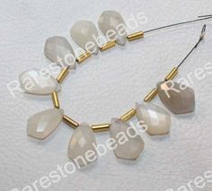 a necklace made out of white glass beads and gold tone metal findings on a white background