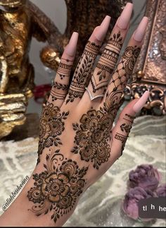 a woman's hand with henna tattoos on it and her hands in the middle