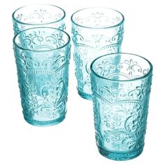 four blue glass tumblers sitting next to each other on a white surface with an ornate design