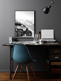 a desk with a chair, lamp and pictures on the wall in front of it