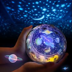 a person holding a glowing orb in their hand with stars and planets on the ceiling