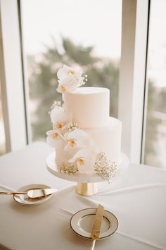 a white wedding cake sitting on top of a table next to a pair of spoons