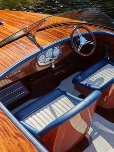 the inside of a speed boat with wood paneling and blue leather seats on it