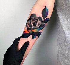 a person with a black rose tattoo on their left arm and the other hand is holding it