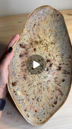 a person holding an old pottery bowl with holes in the middle and a video playing on it