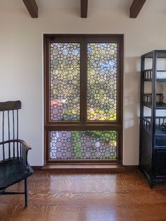 an empty room with a bench and stained glass window on the wall, in front of a bookcase