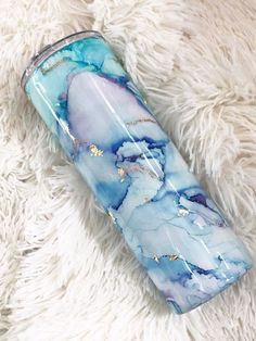 a blue and white marbled glass tumbler sitting on top of a fluffy rug