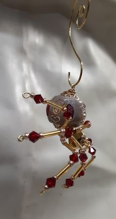 a gold and red beaded ornament hanging from a hook on a white cloth