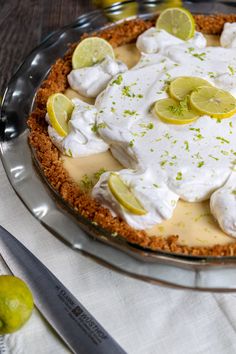 there is a pie with lemons and whipped cream on the top, along with limes