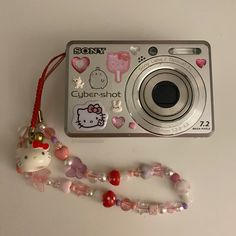 a hello kitty camera sitting on top of a table next to a necklace and bracelet