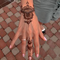 a woman's hand with henna tattoos on it