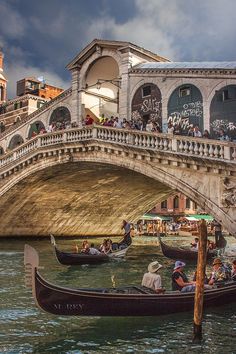 two gondolas with people on them in front of a bridge and some buildings