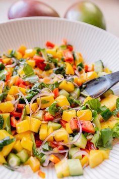 a white plate topped with a salad covered in veggies next to an apple