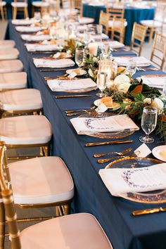 the table is set with blue linens and gold chargers