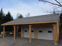 two garages are built in the middle of a gravel lot with trees around them