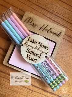 some pencils are sitting on top of a wooden box with a name tag that says, take notes from a high school year