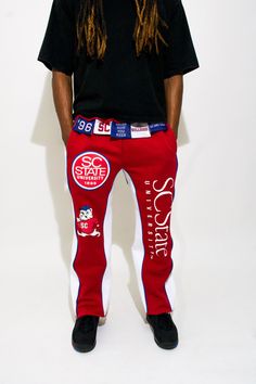 Celebrate the pride and legacy of South Carolina State University with the SC State Tag'Em Up Pants. These sweatpants are designed for Bulldogs who want to showcase their school spirit in style and comfort. Crafted from premium fleece cotton, the pants feature bold garnet side panels and white piping that represent the university’s iconic colors. The puff screen print logos on both legs highlight SC State’s Bulldog mascot and other key emblems, making a statement wherever you go. Perfect for gam Cotton Athleisure Pants For Sports Events, Cotton Bottoms With Letter Print For Sports Season, Cotton Joggers For Streetwear Sports Season, Team Spirit Cotton Bottoms For Sports Events, Collegiate Cotton Bottoms For Streetwear, Sporty Red Cotton Sweatpants, Casual Cotton Bottoms For Sports Events, Cotton Sports Bottoms With Team Spirit Style, Varsity Cotton Sweats For Streetwear