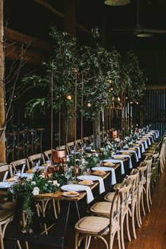 a long table set up with place settings and greenery