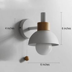 a white wall light with a wooden top on the left side and a small round light fixture on the right side