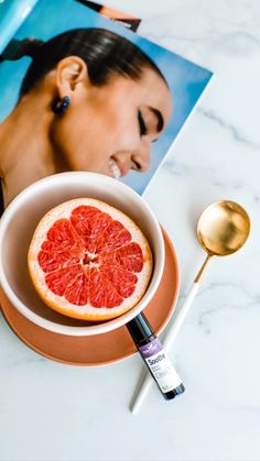 a grapefruit in a bowl with a spoon next to it on a table