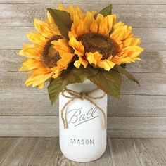 a mason jar filled with sunflowers on top of a wooden table