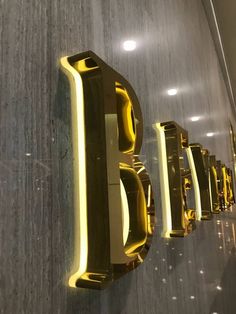 the letters b and f are illuminated in gold on a wall next to each other