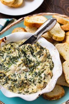 a bowl of spinach dip with bread on the side