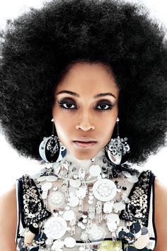 a woman with an afro is posing for the camera and has her hair styled up