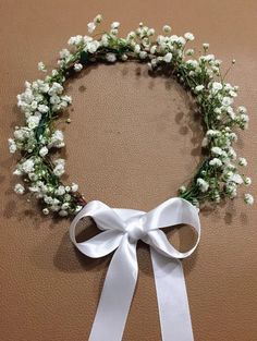 a white ribbon tied around a wreath with baby's breath flowers on the side