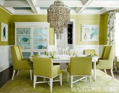 a dinning room with green chairs and a chandelier hanging from the ceiling