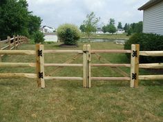 a wooden fence in the grass near a house