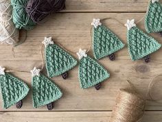 crocheted christmas tree ornaments are displayed on a wooden table next to yarn and twine