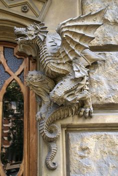 a dragon statue on the side of a building next to a door with a window